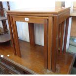 A nest of three retro teak finish tea tables, set on moulded square legs