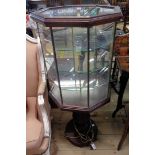 A 17" pedestal vitrine of octagonal design with central illumination and glass shelves, set on a