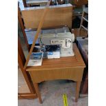 A late 1960's Singer 457 sewing machine with teak effect stowing table, attachments and