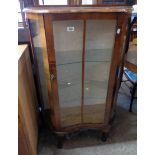 A 29" mid 20th Century polished walnut serpentine front display cabinet with glass shelves