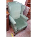 A modern wing back armchair in the antique style with studded jade green velour upholstery, set on