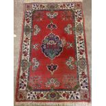 A Middle Eastern wool rug with central medallion and all over floral decoration - faded and worn