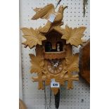 A modern blonde wood cuckoo wall clock with animated figures, musical and triple weight driven