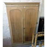 A 4' 1" Victorian stripped pine double wardrobe with moulded cornice and pair of arched panel