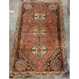 An Iranian wool rug with three central medallions and floral spandrels in geometric border on red