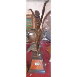An Art Deco style bronzed figurine of a lady with her arm in the air, on a stone plinth