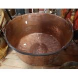 A large copper pan with hammered decoration and swing iron handle