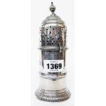 A 7" ornate silver sugar caster with bayonet closing cap, dented finial and reeded circular foot -