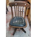 A vintage oak framed lath back swivel office chair with remains of rexine seat panel and Stone's