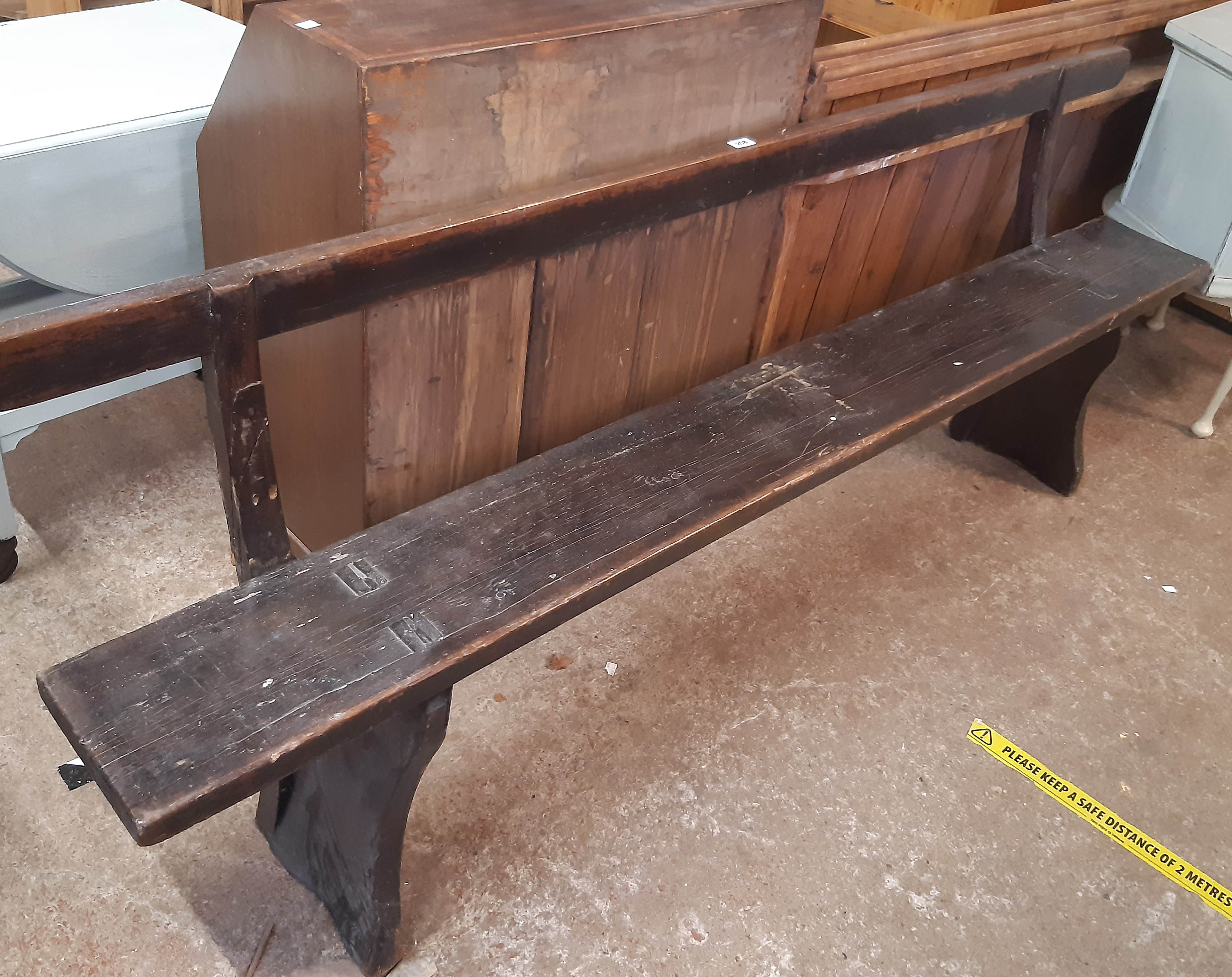 A 7' antique stained pine long plank bench with back rail and splayed shaped standard ends - one