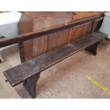 A 7' antique stained pine long plank bench with back rail and splayed shaped standard ends - one