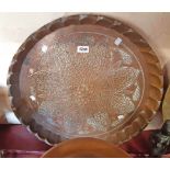 A large embossed copper tray with stylized flower head design