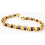A marked 18K yellow metal bracelet, set with double baguette sapphires interspersed with brilliant