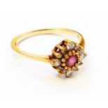 A hallmarked 375 gold ring, set with central small ruby within a diamond encrusted border