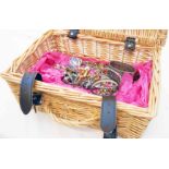 A modern wicker basket containing a small collection of assorted costume jewellery