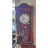 A 20th Century stained oak cased wall clock with part glazed panel door and eight day gong