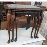 A nest of three reproduction mahogany table with glass inset tops, set on acanthus cabriole legs