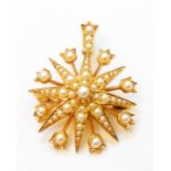 A 3cm diameter old yellow metal starburst pattern and seed pearl encrusted pendant/brooch