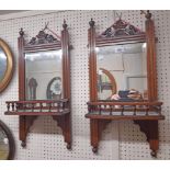 A pair of Edwardian walnut framed wall mirrors, each with decorative pediment and spindle gallery to