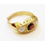 A hallmarked 750 gold ring with central garnet flanked by two diamonds in boat shaped setting