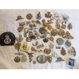 A collection of military and other cap badges including The Royal Sussex Regiment, ARP, vintage Ford