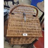 A wicker picnic hamper with carrying handle and bi-folding top