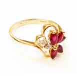 A hallmarked 585 gold stylised flowerhead pattern ring, set with five rubies and two small diamonds