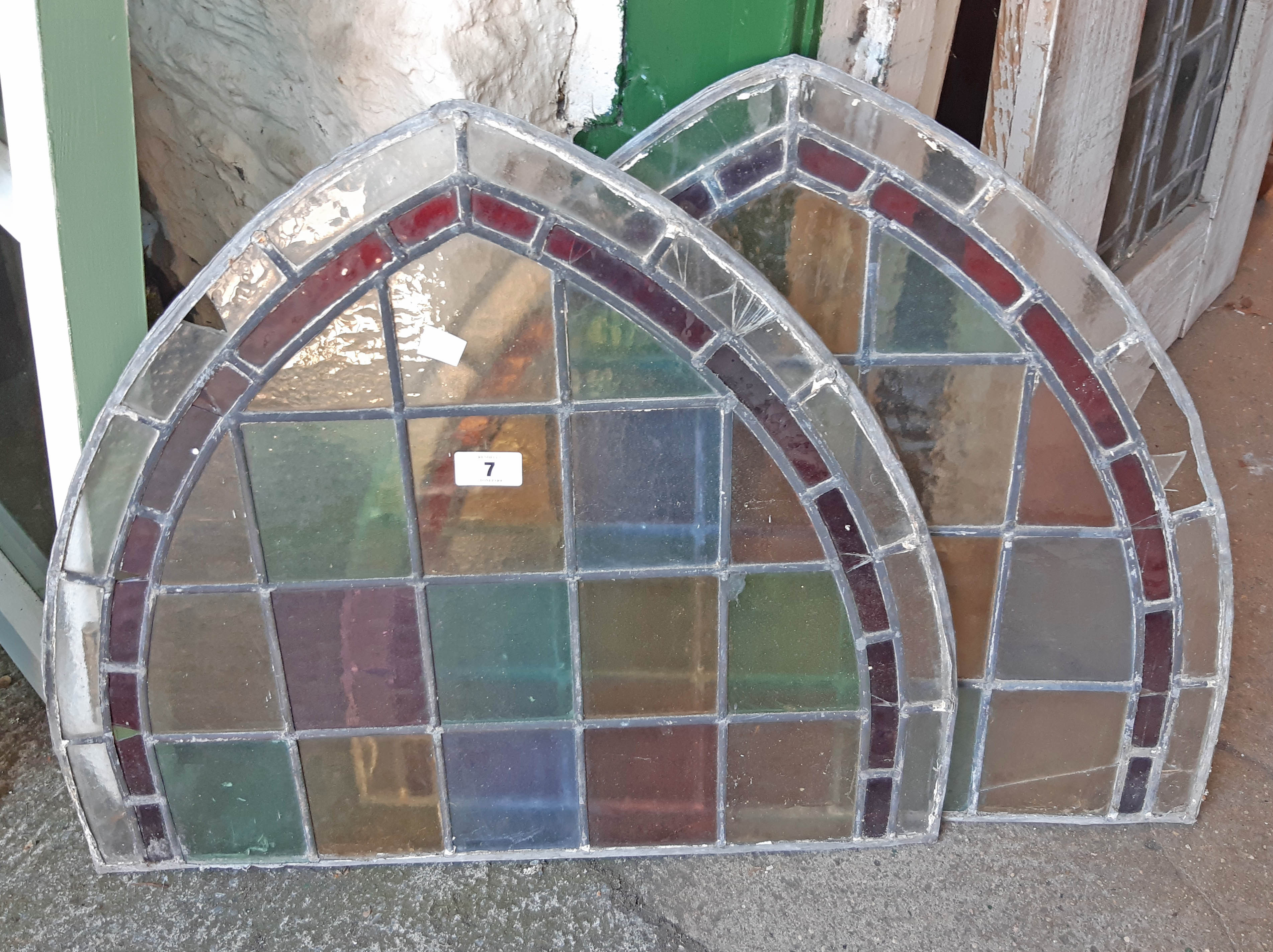 Two stained and leaded glass window panels with arched tops - some damage