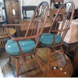 A set of four Ercol dark stained elm high hoop stick back chairs with pierced swan splats and
