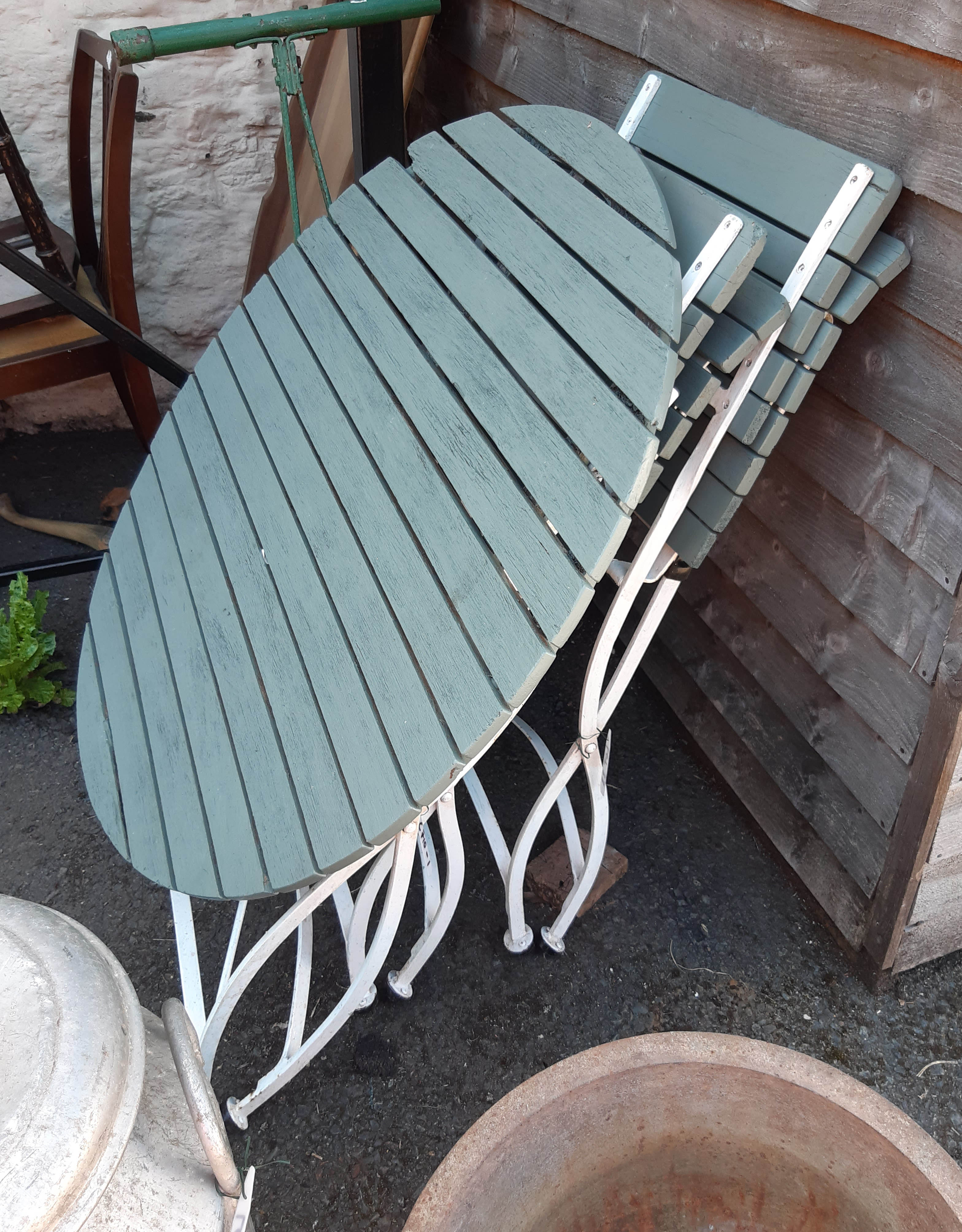 A wrought iron and wooden folding garden table and two chairs