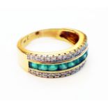 A marked 750 yellow metal ring, set with row of paved emeralds and two rows of tiny diamonds