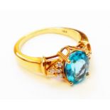 A hallmarked 750 gold ring, set with large central oval blue topaz flanked by eight tiny diamonds