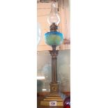 A brass column table oil lamp with moulded textured blue glass reservoir