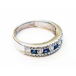 A hallmarked 375/9 white gold ring, set with half band of sapphires and diamonds with further tiny