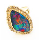 A marked 14K/585 yellow metal ring, set with shaped opal within a diamond encrusted border
