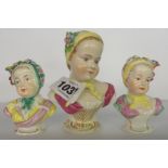 Three small German porcelain busts of children decorated with applied flowers - largest bearing
