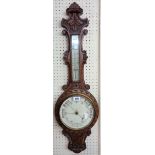 A Victorian ornate carved oak cased banjo barometer/thermometer with printed scale and dial, pierced