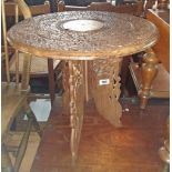 A 18" 20th Century Indian tripod table with profuse carved and inlaid decoration to top, set on a