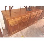 A 5' 11" modern waxed pine dresser base with four frieze drawers and quadruple panelled cupboard