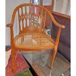 A stained walnut framed bow elbow chair with fret-cut back and rattan seat panel, set on moulded