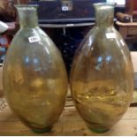 A pair of large elongated carboy glass bottles