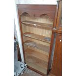 A 33 1/2" stained mixed wood six shelf open bookcase with shaped top apron and plinth base