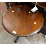 A 24" diameter figured walnut topped low pedestal table, set on ebonised turned pillar and tripod