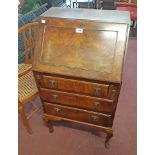 A 21" 20th Century walnut bureau with part fitted interior and three drawers under, set on