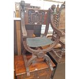 A 20th Century stained wood framed X-frame armourial elbow chair with carved applied lion mounts