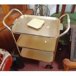 A vintage Carefree three tier tray-top tea trolley with golden finish - circa 1960