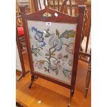 An Edwardian walnut framed fire screen with applied decoration and floral woolwork panel under