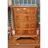 A 19 1/2" reproduction mahogany bow front bedside chest of four long drawers, set on bracket