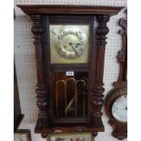 An early 20th Century stained wood cased regulator style wall clock with visible pendulum,