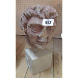 An antique carved stone head, set on later base